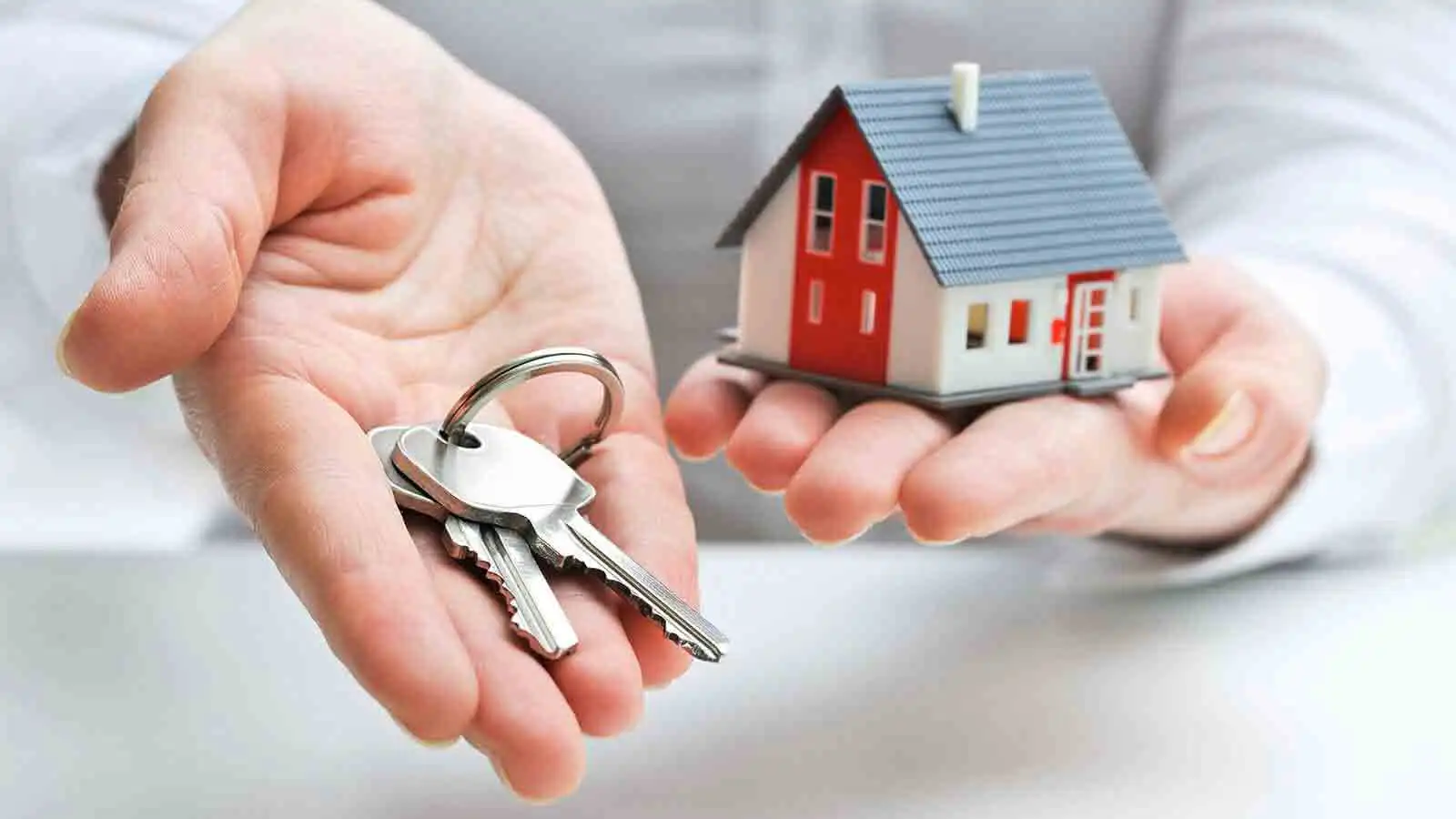 keys and tiny house in palms of hands